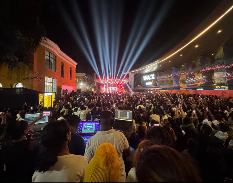 Large live event crowd beneath beams of stage light